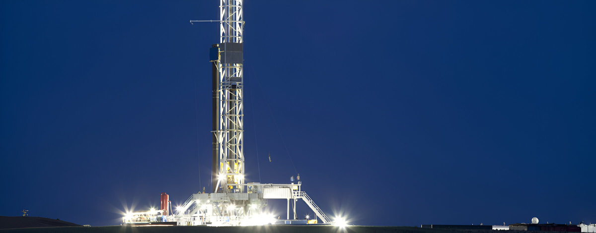 A drilling rig is lit up at night.