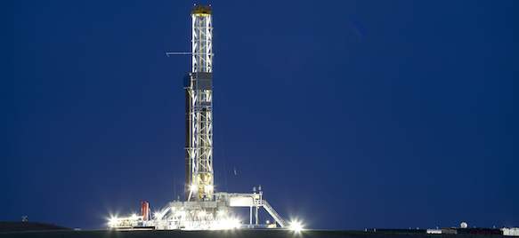 A drilling rig is lit up at night.