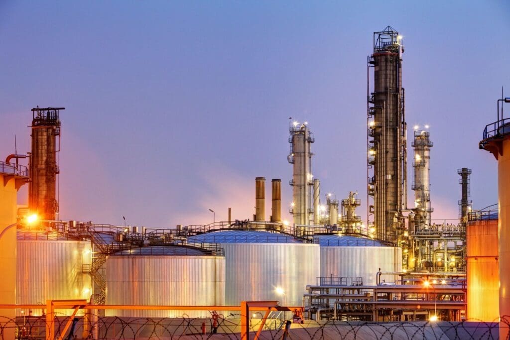 A group of large oil tanks in front of an industrial plant.