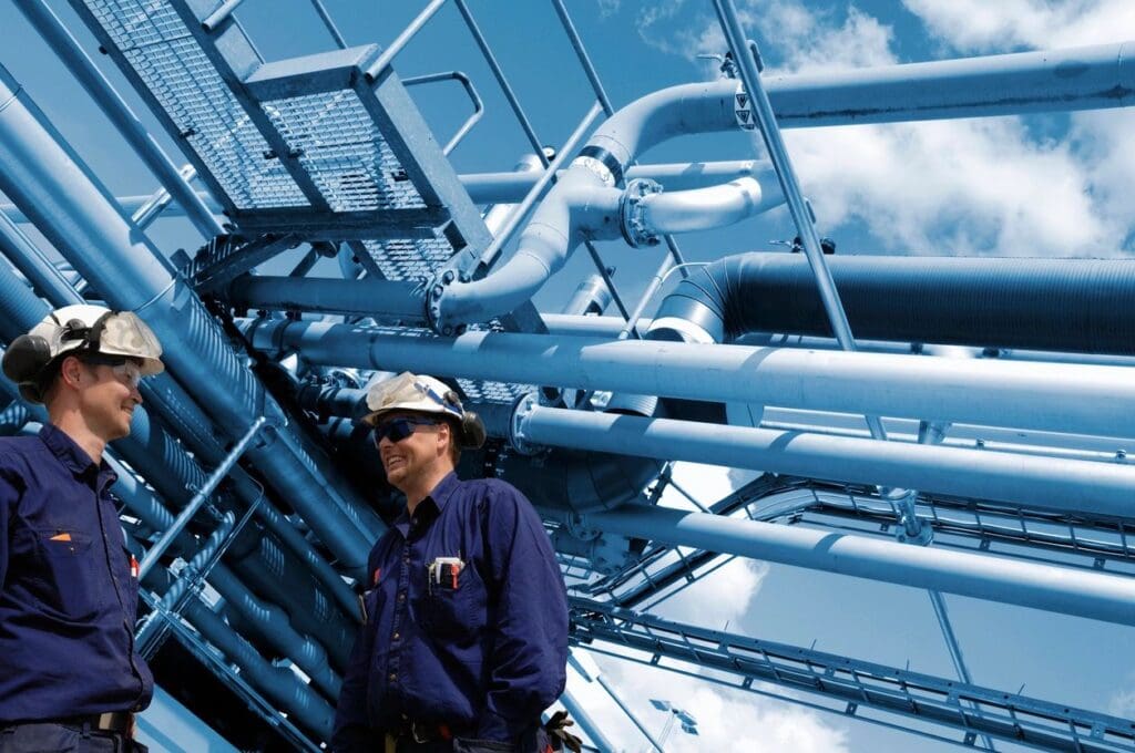A man standing in front of pipes and wires.